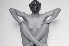 CORPS-SCULPTURE au carré jouant du coude avec masque